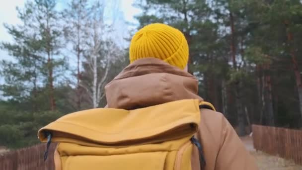 Marco trasero de un joven viajero con mochila amarilla caminando por el bosque. — Vídeos de Stock