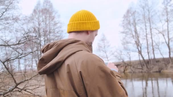 Rückenbild eines jungen Reisenden mit gelbem Rucksack, der im Wald spazieren geht. — Stockvideo