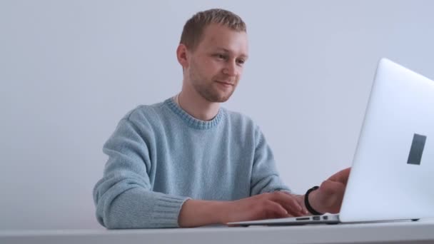 Jonge mooie man werken of studeren online met behulp van laptop en notities maken. — Stockvideo