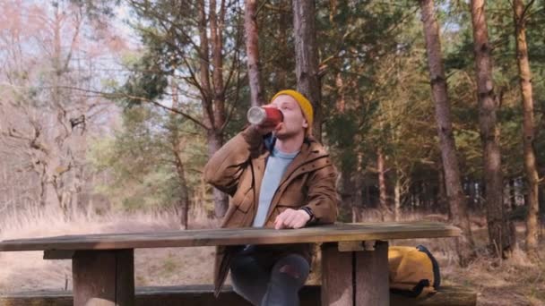 Genç erkek gezgin nehir kenarında oturmuş çay içiyor ve hayranlıkla hayranlık duyuyor. — Stok video