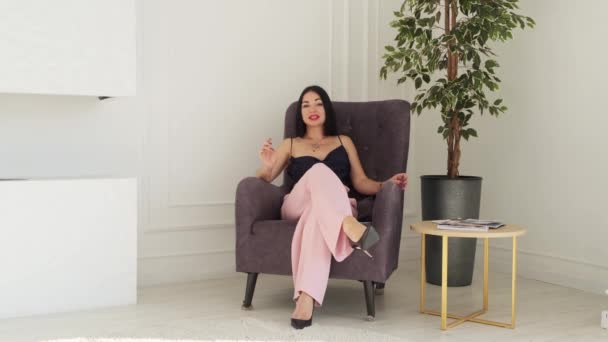 成功した豪華なブルネットビジネスマン女性与えますAインタビューでザ茶色のアームチェアに座って. — ストック動画