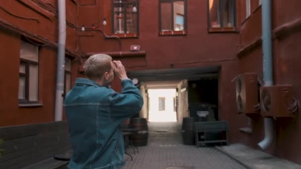 Młody atrakcyjny mężczyzna podróżnik robi zdjęcia stary czerwony budynek. — Wideo stockowe