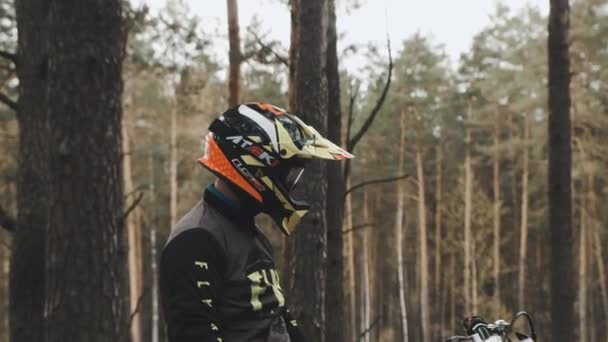 Мотоциклист остановился, чтобы сделать перерыв и отдышаться после тяжелой поездки в лес. Мотокросс в лесу. — стоковое видео