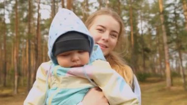 Küçük bebek annesine sarılıp bahar ormanlarını keşfederken kameraya bakıyor..