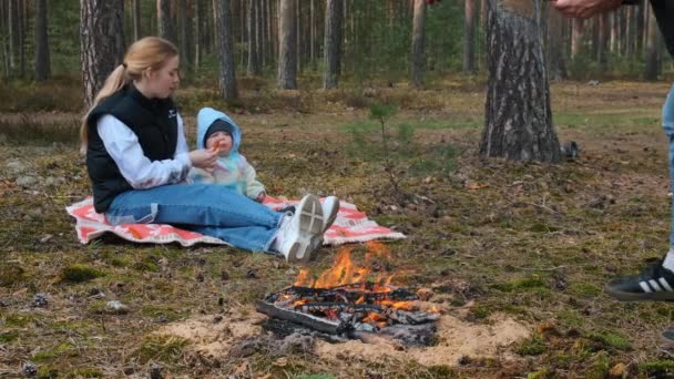 Mały chłopiec i jego mama na pikniku w wiosennym lesie sosnowym, siedzący przy ognisku na dywanie.. — Wideo stockowe