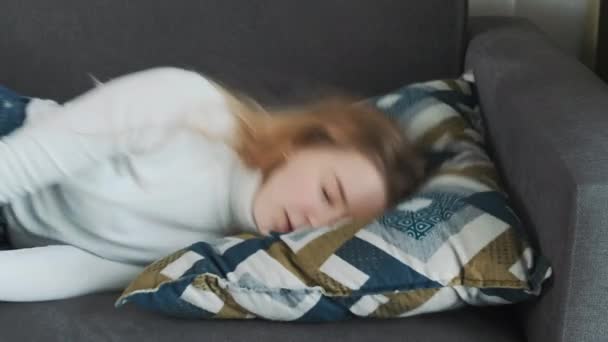 Young european exhausted or bored female literally falls on the sofa pillow after a hard working day and falls asleep. — Stock Video