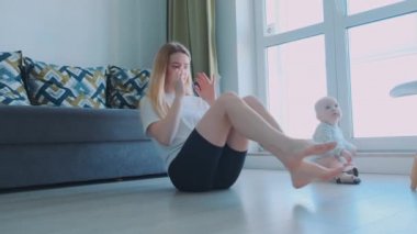 Genç ve enerji dolu anne sabah egzersizlerini evde çocukla yapıyor. Evde egzersiz, güçlü karın kasları..