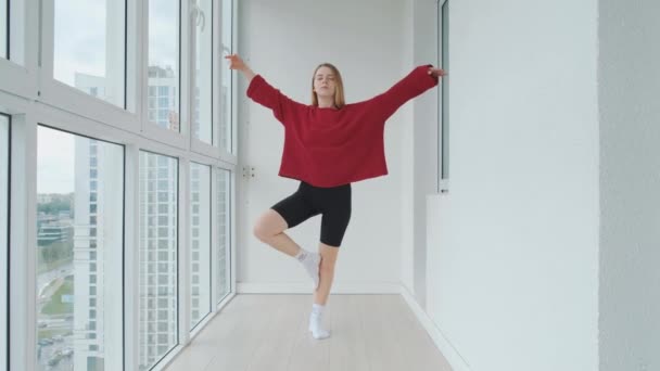 Junges und energiegeladenes Mädchen bei ihren Morgenübungen zu Hause, Yoga oder Stretching. Training zu Hause, starker Körper. — Stockvideo