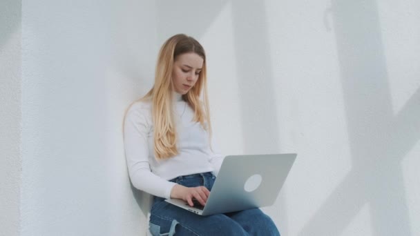 Retrato de uma jovem freelancer europeia sentada na varanda com o laptop multitarefa. — Vídeo de Stock