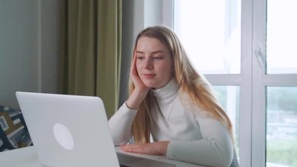 Mladá šťastná atraktivní dívka se usmívá a směje, zatímco má videokall pomocí notebooku. Rozhovor a textování. — Stock video