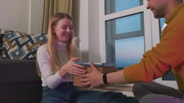 Mladý a šťastný evropský pár otevírá šálek dárkové krabice. Užívají si překvapení a konverzují o svých pocitech. — Stock video