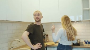 Genç mutlu sarışın Avrupalı çift akşam yemeği pişirirken beyaz modern mutfakta sohbet ediyorlar..