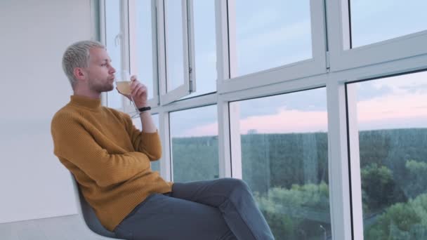 Slow motion shot af a young european guy drinking wine at the balcony enjoying the view and the sunset. — Vídeo de Stock