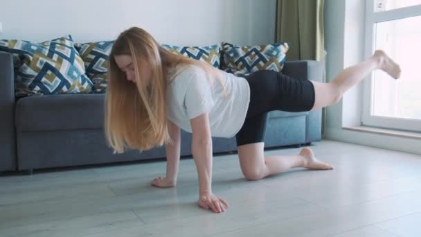 Joven y llena de energía en forma chica haciendo sus ejercicios matutinos en casa con el niño. Entrenamiento en casa, abdominales fuertes. — Vídeo de stock