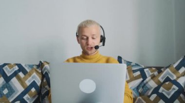 Çevrimiçi çalışan Avrupalı genç bir erkek, müşteriyle konuşuyor ve evdeki kanepede oturan yeni projeleri tartışıyor..