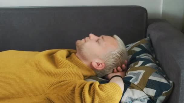 Fiatal európai kimerült vagy unatkozó férfi szó szerint leesik a kanapéra kemény munkanap után, és elalszik.. — Stock videók