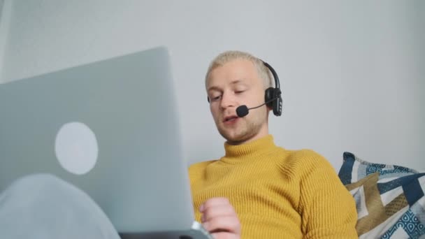 Mladý samec evropské volné noze pracující on-line, mluvit s klientem diskutovat o nových projektech sedí na pohovce doma. — Stock video