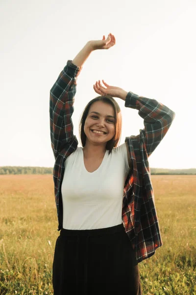 Uma menina feliz com longos cabelos pretos em um campo de trigo. Ele desfruta dos momentos felizes de sua vida. Fotos De Bancos De Imagens