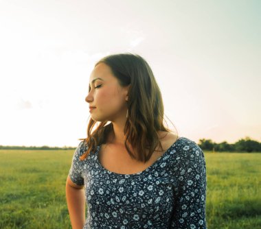 Buğday tarlasında uzun siyah saçlı mutlu bir kız. Hayatının mutlu anlarından zevk alıyor..