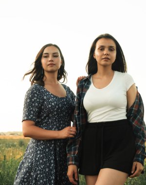 İki kız kardeş doğada yürüyor ve iletişim kuruyor. Gün batımında fotoğraf çekiyorlar..