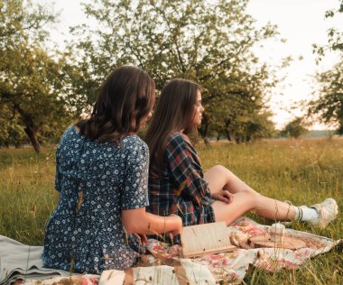 İki kız kardeş doğada yürüyor ve iletişim kuruyor. Gün batımında fotoğraf çekiyorlar..