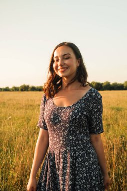 Buğday tarlasında uzun siyah saçlı mutlu bir kız. Hayatının mutlu anlarından zevk alıyor..