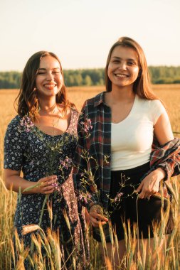 İki kız kardeş doğada yürüyor ve iletişim kuruyor. Gün batımında fotoğraf çekiyorlar..