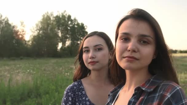 Две сестры ходят по природе и общаются. Они фотографируют на закате.. — стоковое видео