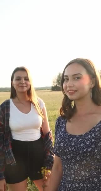 Duas irmãs caminham na natureza e se comunicam. Eles tiram fotografias ao pôr-do-sol. — Vídeo de Stock