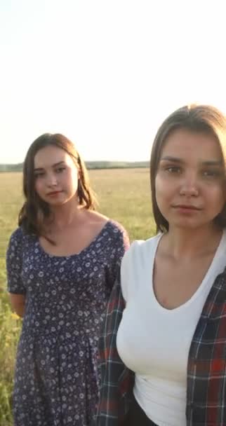 Dos hermanas caminan en la naturaleza y se comunican. Toman fotos al atardecer.. — Vídeos de Stock