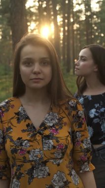 İki genç kız kardeş gizemli bir şekilde kamera merceğine bakıyor. Dikey video.