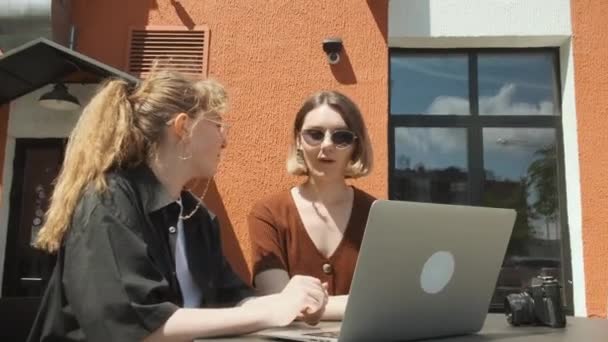 Le ragazze lavorano a distanza in un caffè sulla terrazza estiva. I freelance comunicano con colleghi via collegamento video. — Video Stock