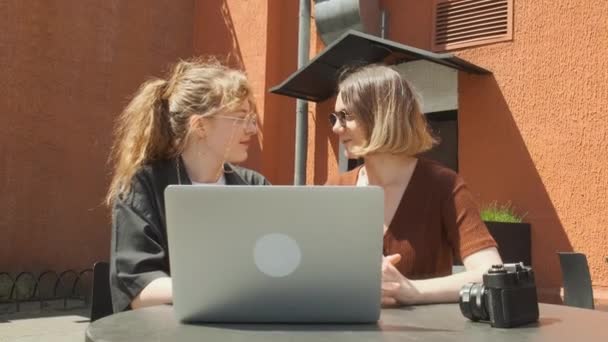 Le ragazze lavorano a distanza in un caffè sulla terrazza estiva. I freelance comunicano con colleghi via collegamento video. — Video Stock