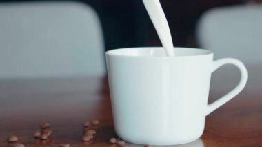 Sabah kahvesine krema döküldü. Bir kahve fincanı. Ürünün yavaş çekim videosu.