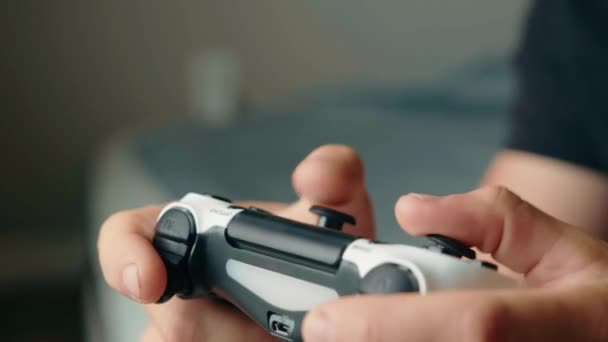 Крупный план рук молодого человека, играющего в видеоигры на игровой консоли — стоковое видео
