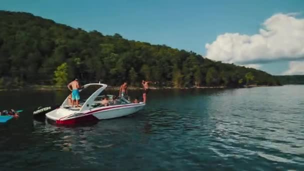 Ein Rahmen aus einer Drohne. Das Boot blieb mitten auf dem Fluss stehen und die jungen Leute springen ins Wasser und haben Spaß. — Stockvideo