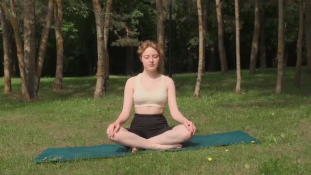 Una giovane ragazza sta facendo yoga in un parco pubblico all'aria aperta. — Video Stock