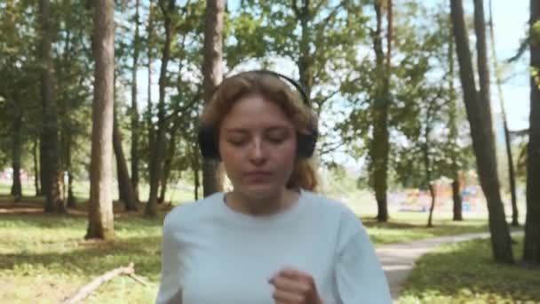 Eine junge Läuferin trainiert im Sommerpark, bereitet sich auf Laufwettbewerbe vor. — Stockvideo