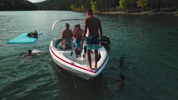 Ein Rahmen aus einer Drohne. Das Boot blieb mitten auf dem Fluss stehen und die jungen Leute springen ins Wasser und haben Spaß. — Stockvideo