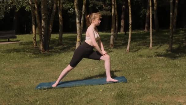 Egy fiatal lány jógázik egy nyilvános parkban a friss levegőn.. — Stock videók