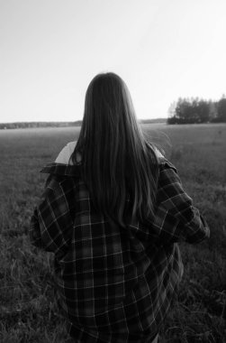 Kızın tarlada yürürken çekilmiş siyah beyaz bir fotoğrafı. Arka görünüm.