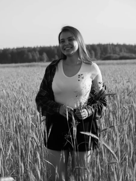 Черно-белая винтажная фотография. Девушка ходит по пшеничному полю и улыбается. — стоковое фото