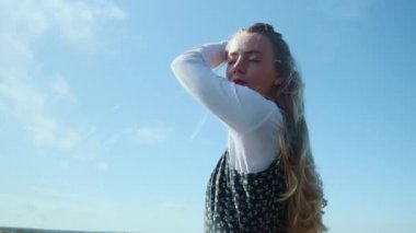 Mavi gökyüzüne karşı güzel elbiseli genç bir kız. Güzel bir kız kameraya poz verir..