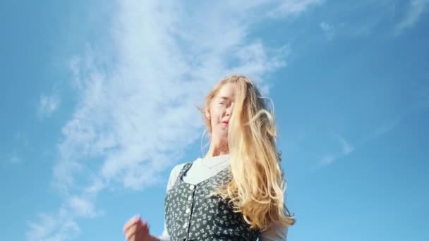 Uma jovem em um belo vestido contra o céu azul. Uma linda garota posa para a câmera. — Vídeo de Stock