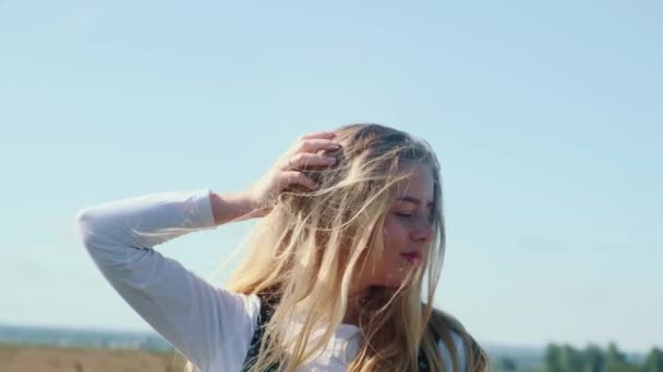 Uma jovem em um belo vestido contra o céu azul. Uma linda garota posa para a câmera. — Vídeo de Stock