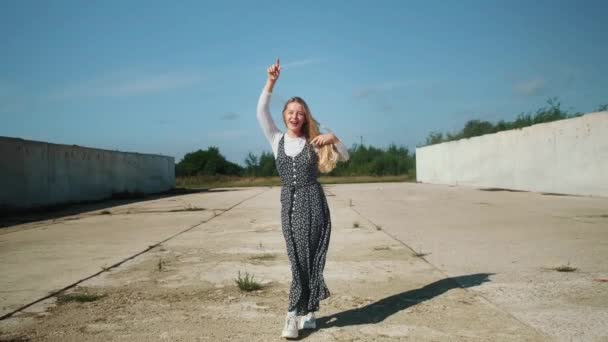 A young girl enjoys freedom. A girl is dancing in a beautiful dress against the background of concrete walls. — Stock Video