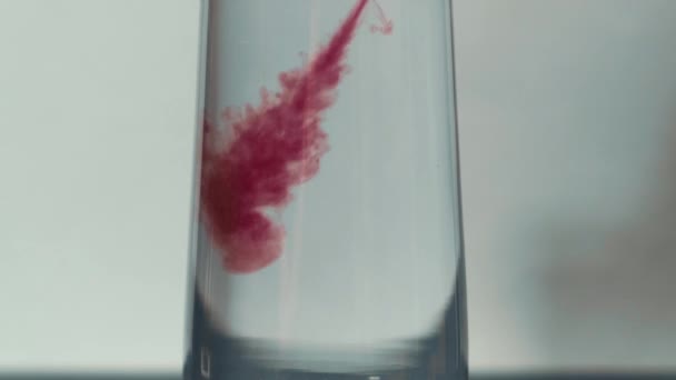 Couleurs rouges abstraites tombant dans un verre d'eau. Potassium Permanganate crystals in water. Fond abstrait dynamique coloré, Mouvement lent — Video