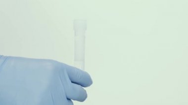 Mavi eldivende kırmızı bir sıvı bulunan cam matara var. Deneyler için malzemeleri karıştırıyorum. Araştırma laboratuarı. Kozmetik ve parfüm üretimi.