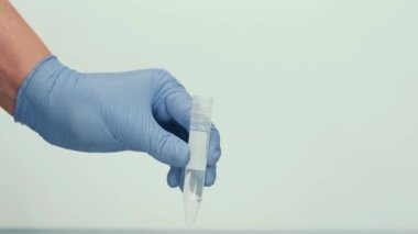 Mavi eldivende kırmızı bir sıvı bulunan cam matara var. Deneyler için malzemeleri karıştırıyorum. Araştırma laboratuarı. Kozmetik ve parfüm üretimi.