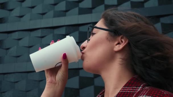 Une jeune fille boit du café à l'air frais. Une fille heureuse boit du café près du centre d'affaires. — Video
